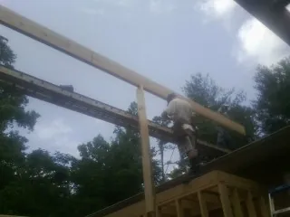 Carpenter setting a ridge beam over a new addition frame — Ice Dam Removal by Roofing Brothers in Hardin