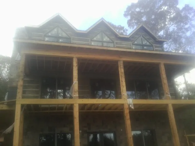 Dormers and porch framing on a large log home under construction — Roof Coating work by our crew in Hardin