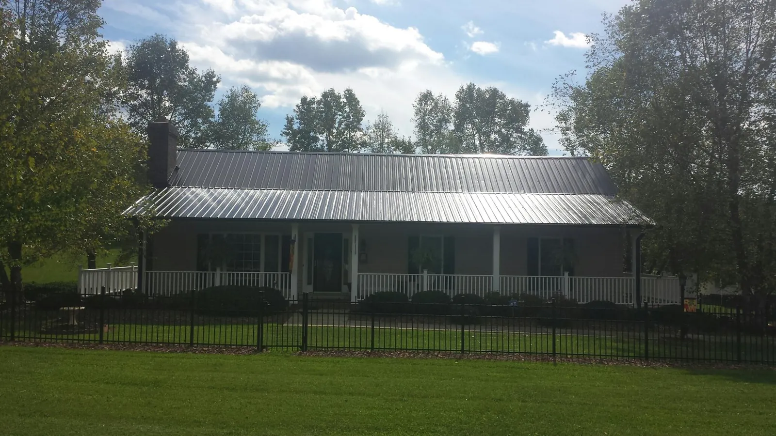 Gray metal roof on a brick ranch with a full width front porch — Gutter Guard Installation work by our crew in Hardin